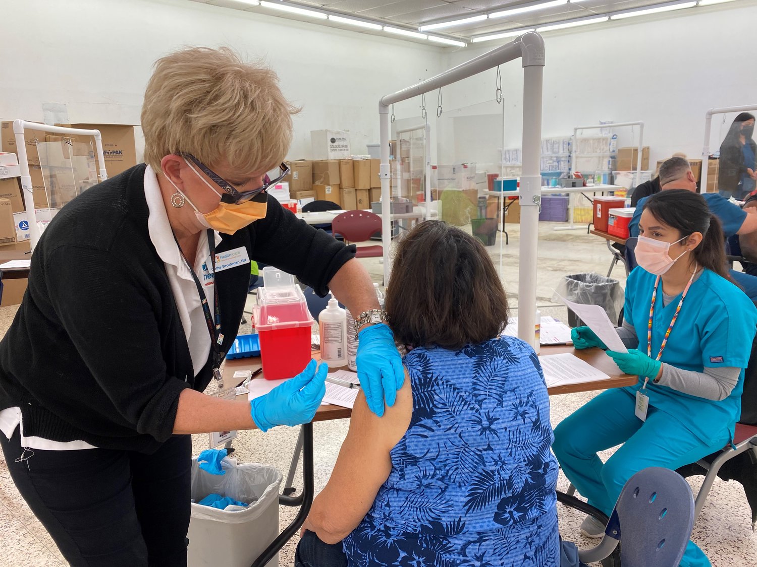 Cathy Brockman of Healthcare Network administers a vaccine at a public event.